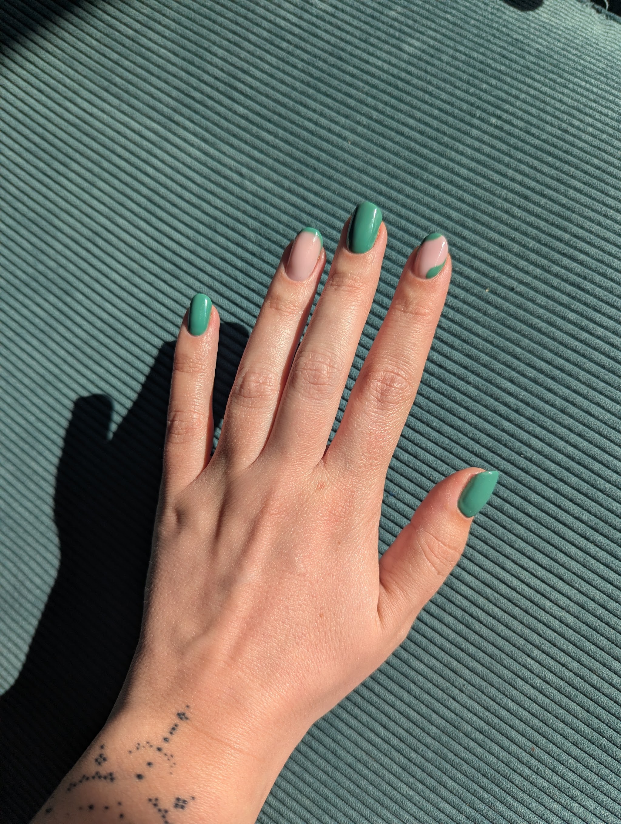 Groene nagels op een hand die op een geribbelde mat ligt