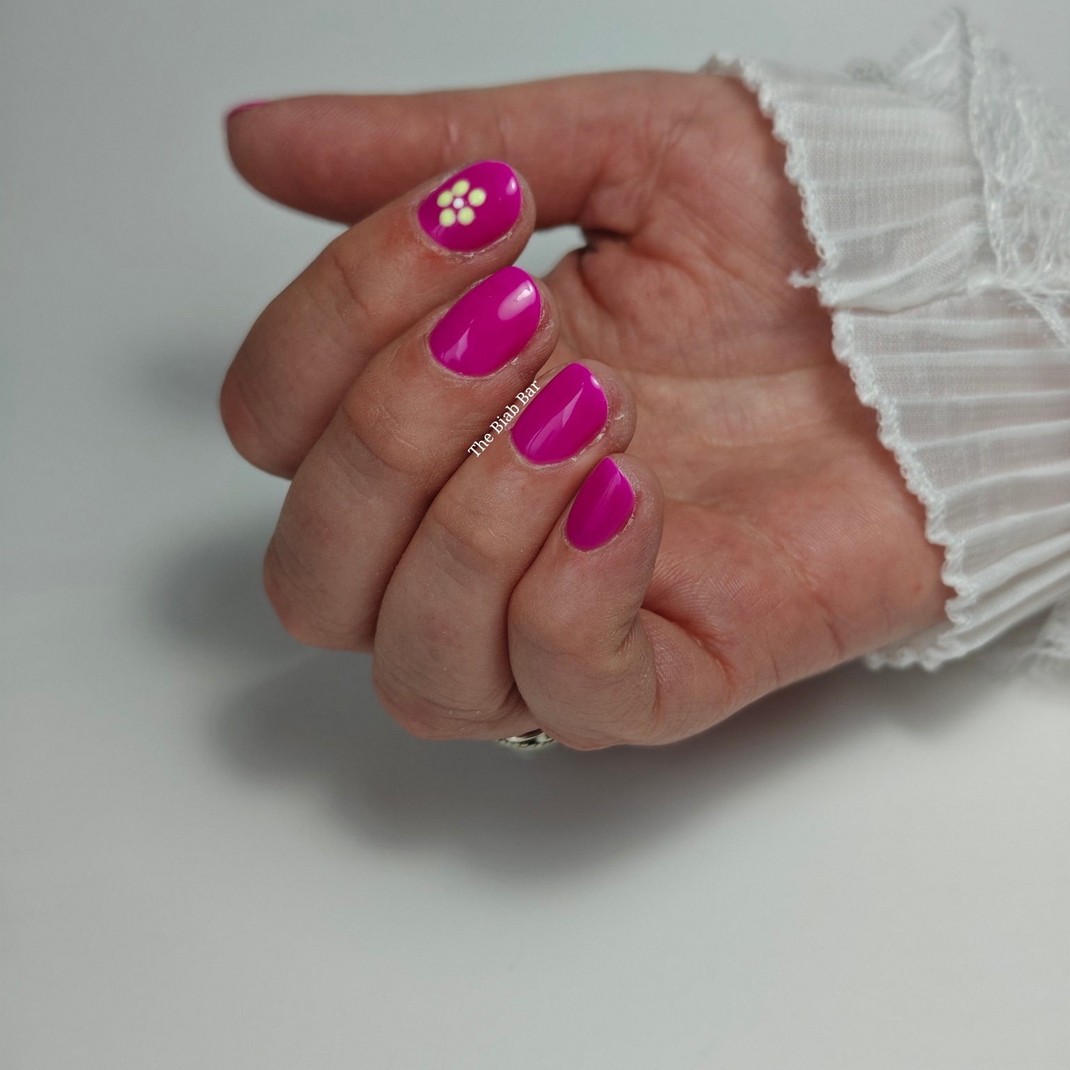 Magenta nagels met op één nagel een geel bloemetje